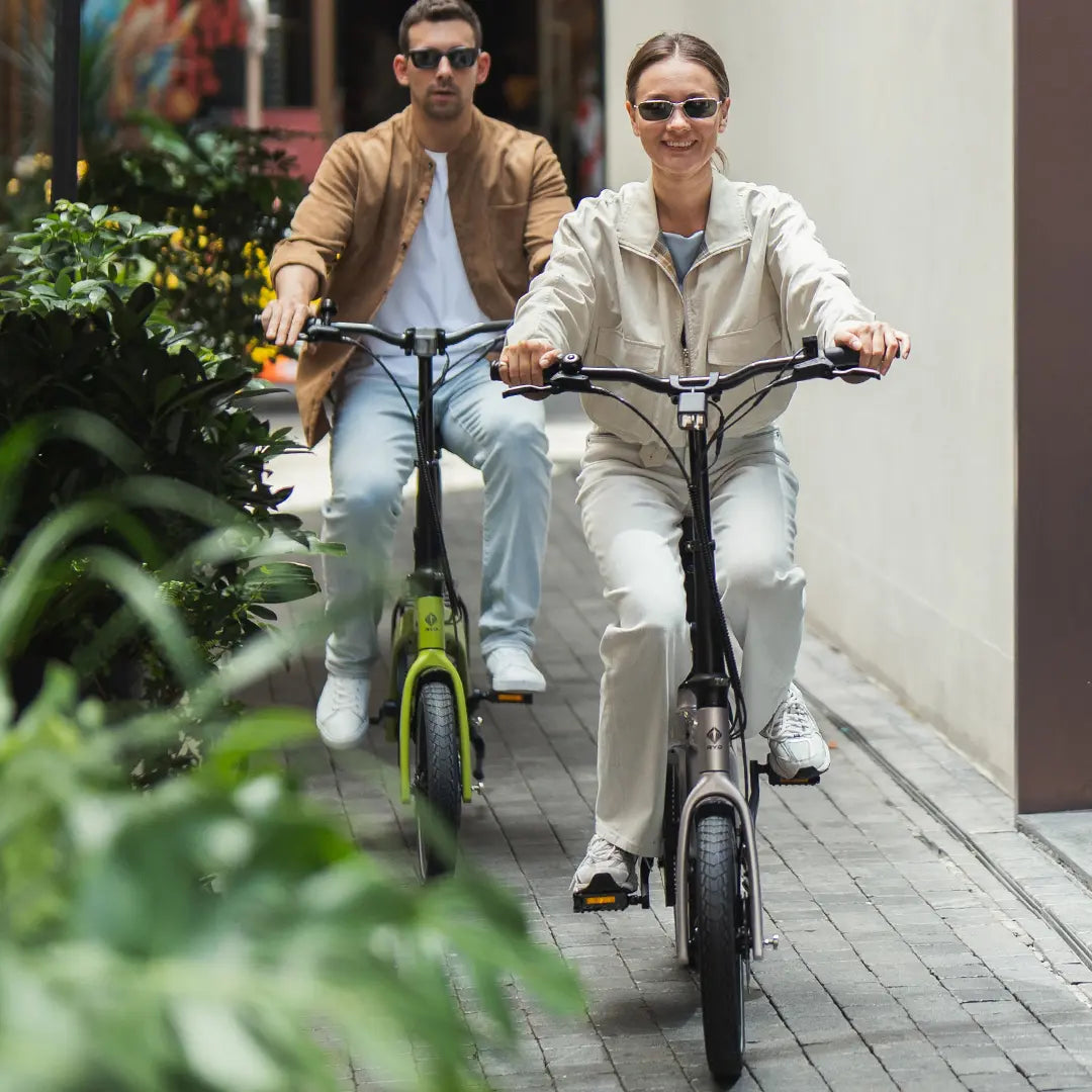 Two riders smiling while riding RYD Aero 16 carbon folding electric bikes through a city street