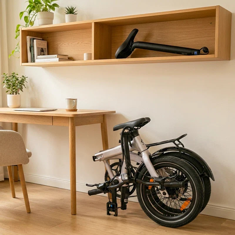 RYD Aero 16 folding electric bike parked beside a desk with the removable seatpost battery stored safely on a clean shelf