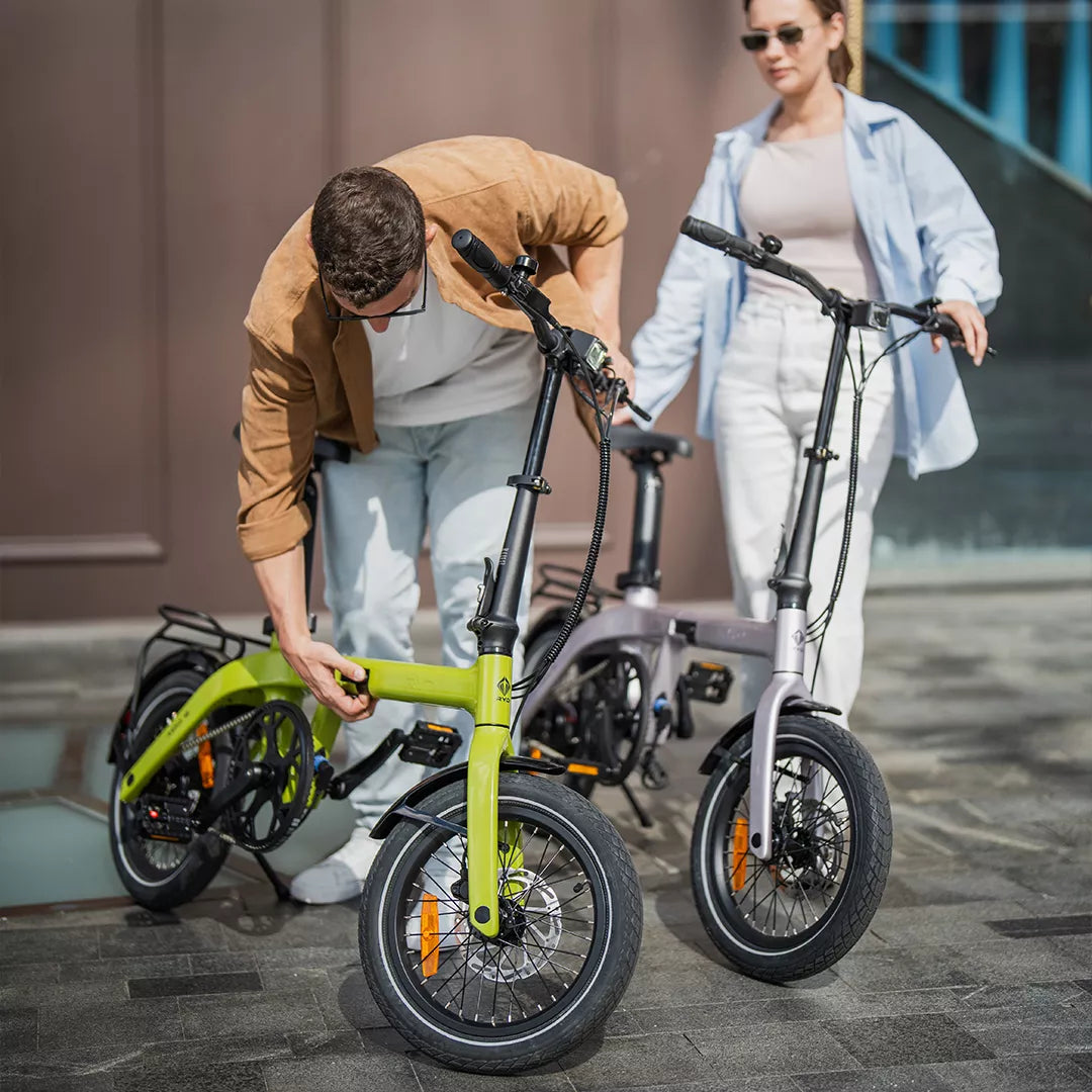 Two riders checking a RYD Aero 16 carbon folding electric bike during an urban cycling stop