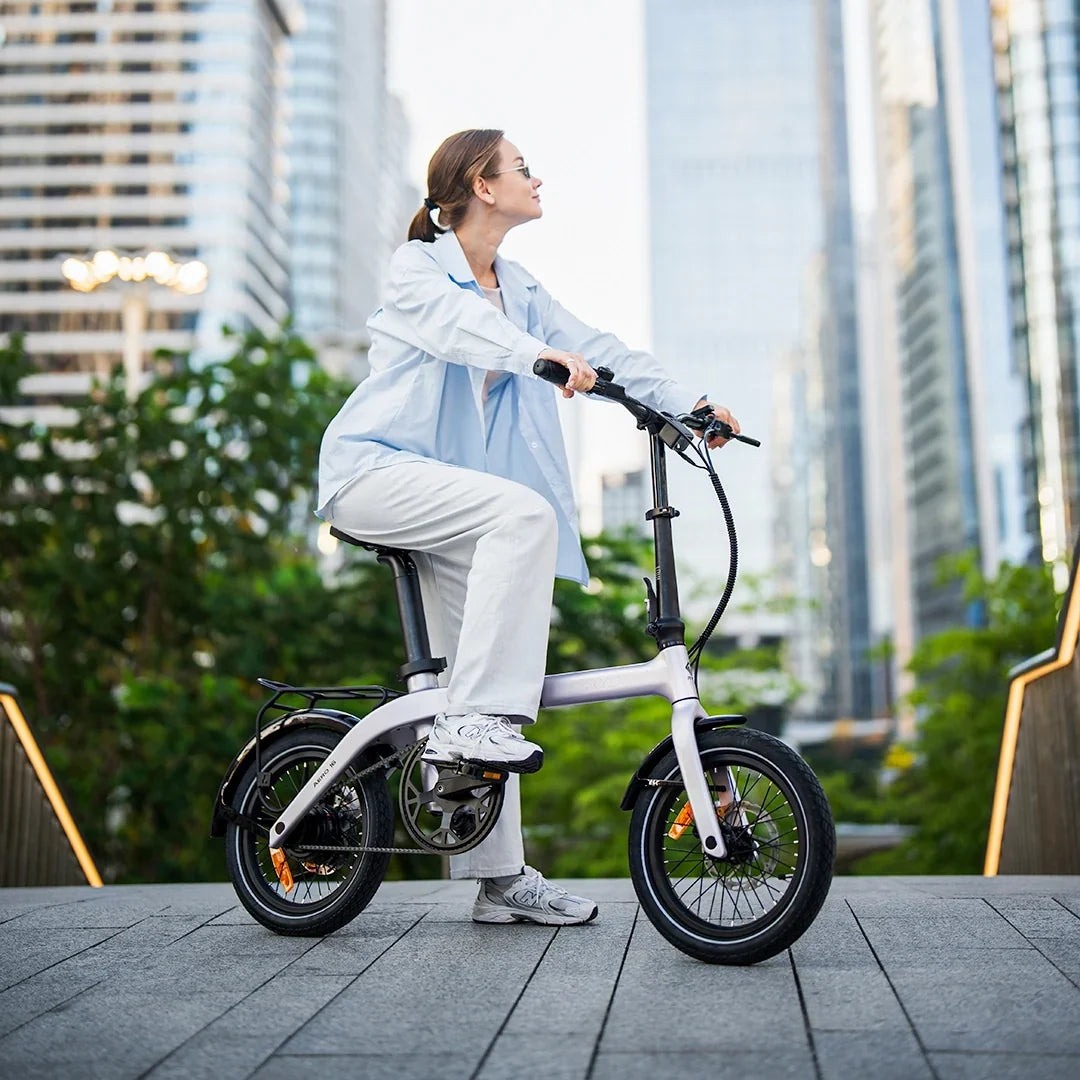 Woman rider standing with RYD Aero 16 carbon folding electric bike in the city and enjoying a relaxed urban cycling moment